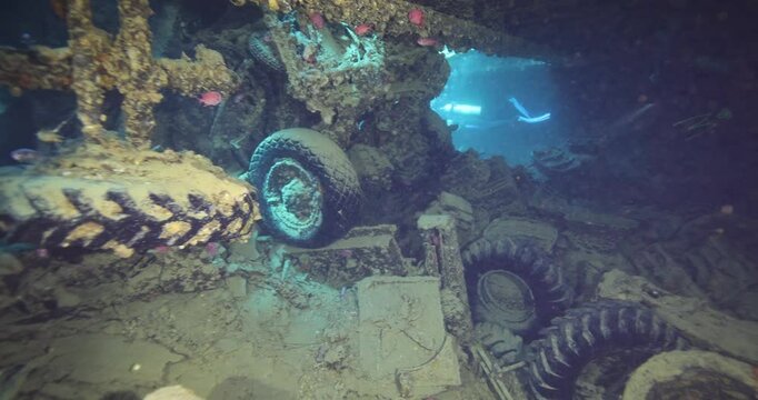 Divers explore the wreck of the SS Thistlegorm. Top diving wreck dives. Swimming over motorbikes and other cargo in hold of Thistlegorm shipwreck in the Red Sea, Sharm el Sheikh, Egypt.