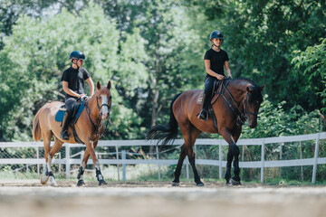 Two riders on horseback enjoying a sunny day, riding along a peaceful trail surrounded by green...