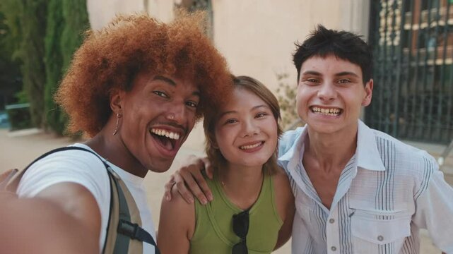Close-up of three joyfull friends taking pictures selfies on the street, laughing at the camera
