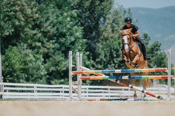 Equestrian rider on a horse jumping over a colorful obstacle during an outdoor competition. The image captures the thrill and skill of show jumping.