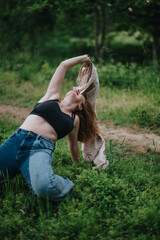 Obraz premium A woman in a casual outfit enjoys freedom and joy while stretching in a green outdoor setting, embracing nature's tranquility.