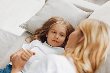 Mother and daughter sharing a tender moment on the couch, gazing into each other's eyes with love and warmth