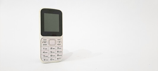 White old handphone on white background. This phone has a classic design before the smart	
