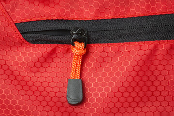 Zipper Closure made of orange rope on a red back pack © Renhue