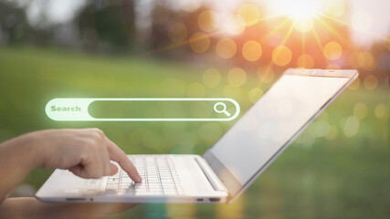 A person is typing on a laptop with a search bar on the screen
