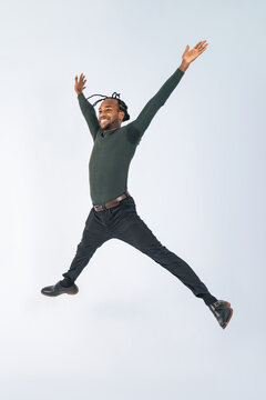 Full body photo of a black man jumping in front of a white background