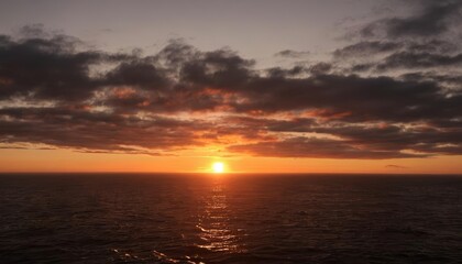 Obraz premium Sunset over the ocean casting a warm glow on the horizon