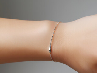 A close-up of a delicate silver bracelet on a wrist against a soft gray background. The minimalist design emphasizes elegance and simplicity, perfect for jewelry mockups and fashion presentations.