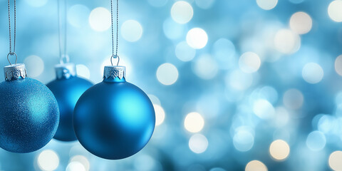 Three hanging blue Christmas baubles on a light blue bokeh background, creating a festive and serene atmosphere. Perfect for holiday cards, winter designs, or seasonal promotions with ample copy space