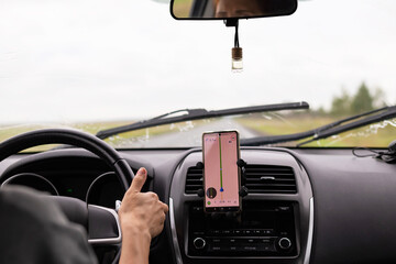 Rear view of a young traveler using a navigator on a mobile phone behind the wheel of a modern car .