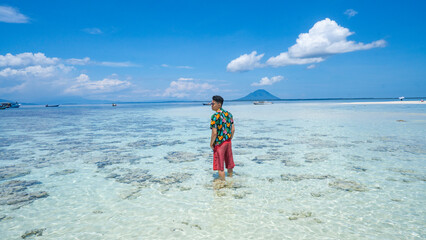 Tropical Island Paradise Nain Mando. Man Standing in Clear Shallow Water. A lone man stands in the...