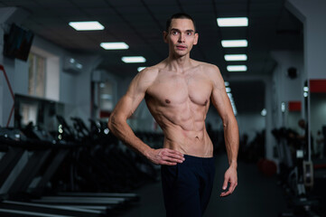 Shirtless man with sculpted body in the gym. 