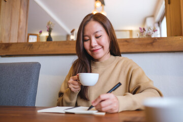 Portrait image of a young woman writing on a notebook on the table