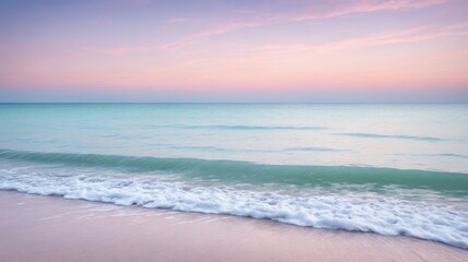 Obraz premium Serene ocean waves gently lapping against a tranquil beach under a pastel-hued sunset sky. Calming seascape with soft, pink and blue colors, perfect for relaxation and peaceful nature themes.