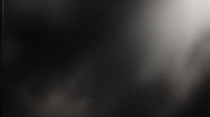 Black matte textured background with floating dust particles illuminated by soft light in the top right corner, creating a deep contrast between black and white. This abstract design emphasizes textur