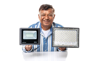 Asian senior man smiling holding LED spotlights isolated on white background, renewable energy,...