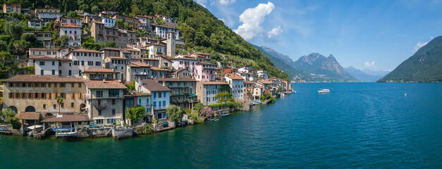 Aerial panoramic drone shot of the stunning ancient village Gandria on Lake Lugano, surrounded by the mountains of southern Switzerland