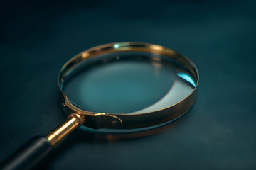 Closeup of a Goldrimmed Magnifying Glass on a Teal Surface