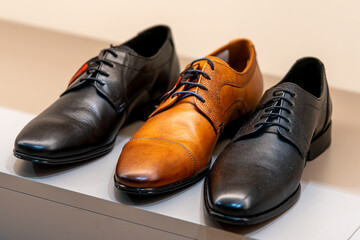 Men's fashion shoes on display in a store window in a shopping mall.