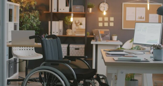 Contemporary wheelchair at desk in office prepared workplace for disabled employee. Inclusive company and accessibility for handicapped concept.