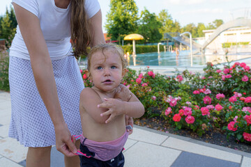 Fototapeta premium Mother changes little girl's clothes after swimming by the pool.