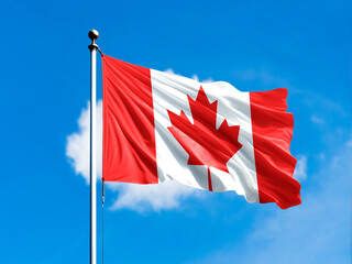 Canada flag flying on blur blue clouds background.
