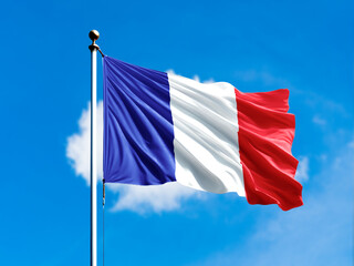 France flag flying on blur blue clouds background.