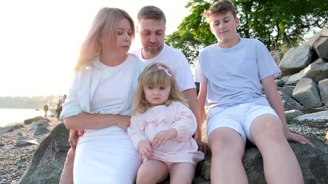Family holiday near the sea. Father, mother and little daughter on beach. dad mom little daughter beach sit