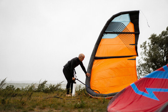 A man packs up his kite surfing equipment as a storm approaches.