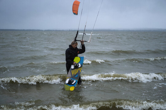 Woman packs up his kite surfing equipment as a storm approaches.
