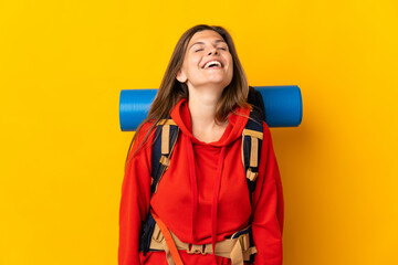 Slovak mountaineer woman with a big backpack isolated on yellow background laughing