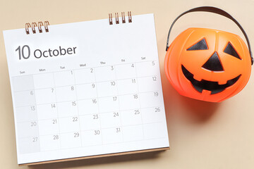 October 2024 calendar schedule ,  October 2024 calendar and Jack'O pumpkin basket on pastel beige background. Welcoming Halloween concept.