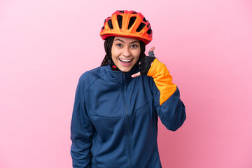 Teenager cyclist girl isolated on pink background making phone gesture. Call me back sign
