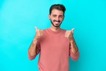 Young caucasian man isolated on blue background with thumbs up gesture and smiling