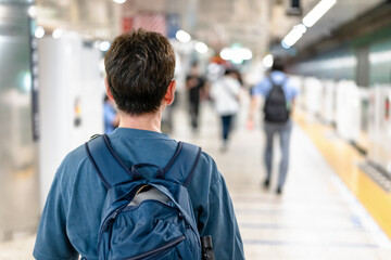 駅のホームで電車を待つ男性