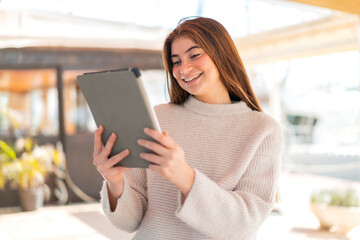 Young pretty caucasian woman holding a tablet with happy expression