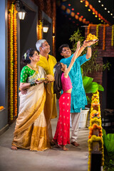 Naklejka premium Indian parents with children celebrating Diwali on the balcony, holding Pooja thali and sweets.