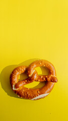 Festive Bavarian pretzel against a bright yellow background, perfect for Oktoberfest celebration concepts and traditional German cuisine themes