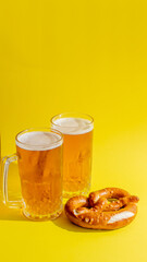 Two frothy beer mugs and a pretzel on a vibrant yellow background, celebrating Oktoberfest, the German beer festival