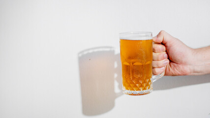 Hand holding a frosty mug of beer casting a shadow, perfect for Oktoberfest, happy hour, or summer celebrations