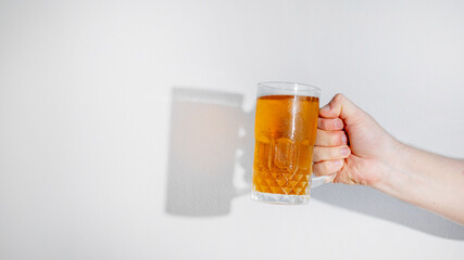 Hand holding a frosty beer mug against white background, ideal for Oktoberfest celebration themes