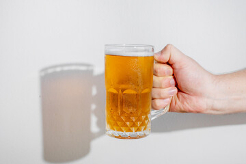 A hand holding a frosty mug of beer, perfect for celebrating Oktoberfest or any casual social gathering