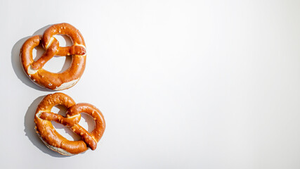 Two freshly baked pretzels on a plain background, evoking the festive spirit of Oktoberfest and traditional German cuisine
