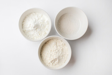 Three white ceramic bowls of different baking powders, essential for holiday cookie baking and accurate ingredient measurement