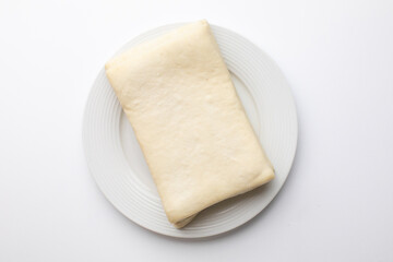 Unbaked puff pastry sheet on a white plate, perfect for holiday baking or pastry recipe concept
