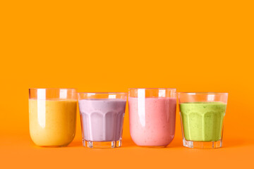 Glasses of different fresh smoothie on orange background