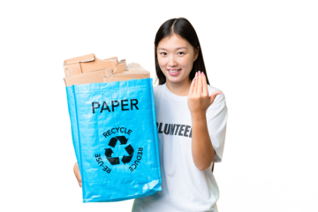 Young Asian woman holding a recycling bag full of paper to recycle over isolated chroma key background inviting to come with hand. Happy that you came