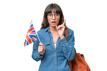 Young caucasian woman holding an United Kingdom flag over isolated background intending to realizes...