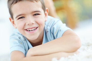 House, relax and portrait of child on carpet for weekend enjoyment, break and development. Happy, boy and face of kid by mat on floor of home for satisfaction, wellness and peace with fun in morning