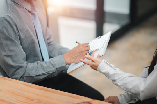Professional business meeting with a person handing over a document for signature in a modern office environment.
